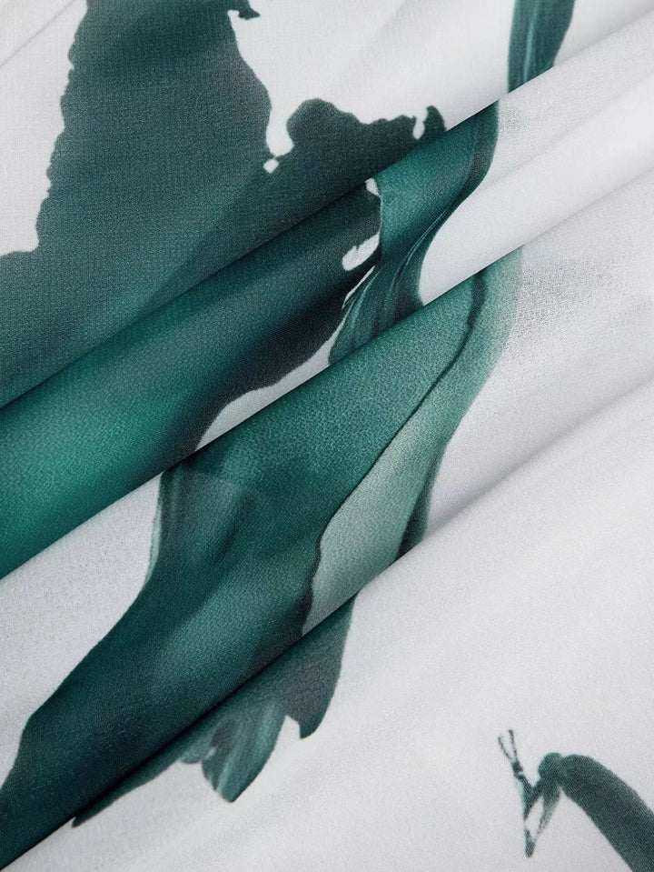 Close-up of flowing fabric with artistic teal print, showcasing texture and design details.