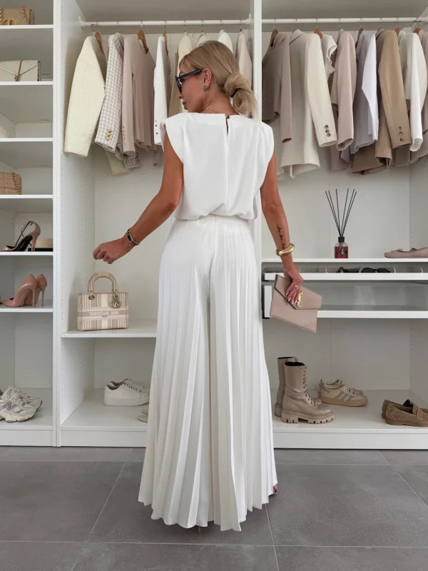 Back view of woman in an elegant white two-piece set with flowy wide-leg pants, in a well-organized wardrobe space.