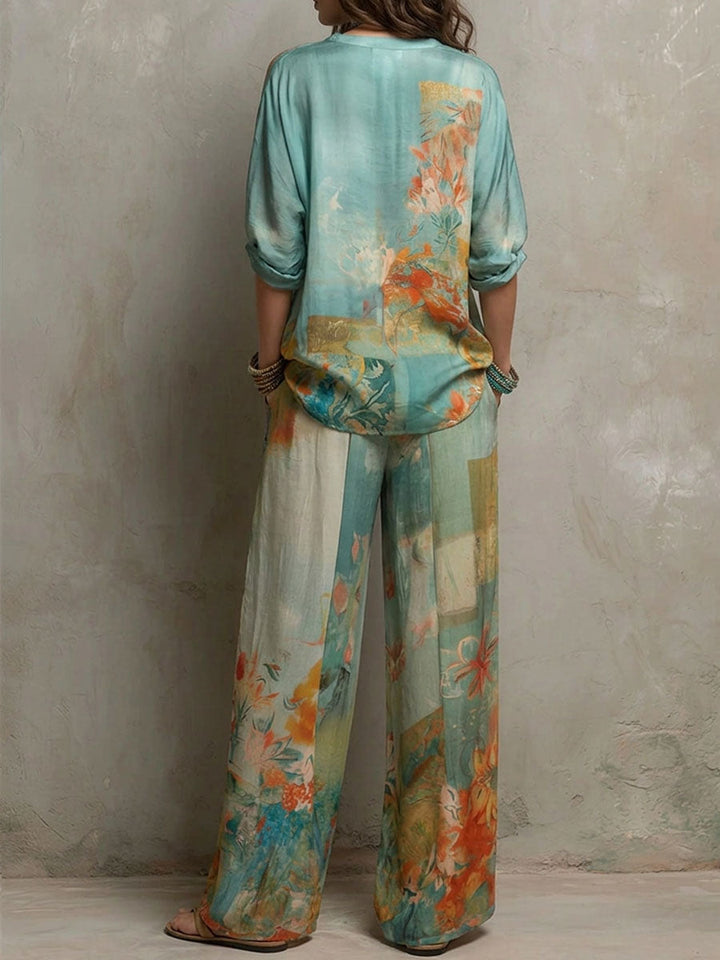 Back view of a woman in a teal and orange floral blouse and pants set, against a textured wall background.