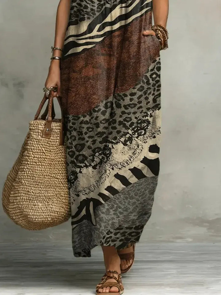 Lower view of mixed print maxi dress with woven bag and sandals in studio setting.