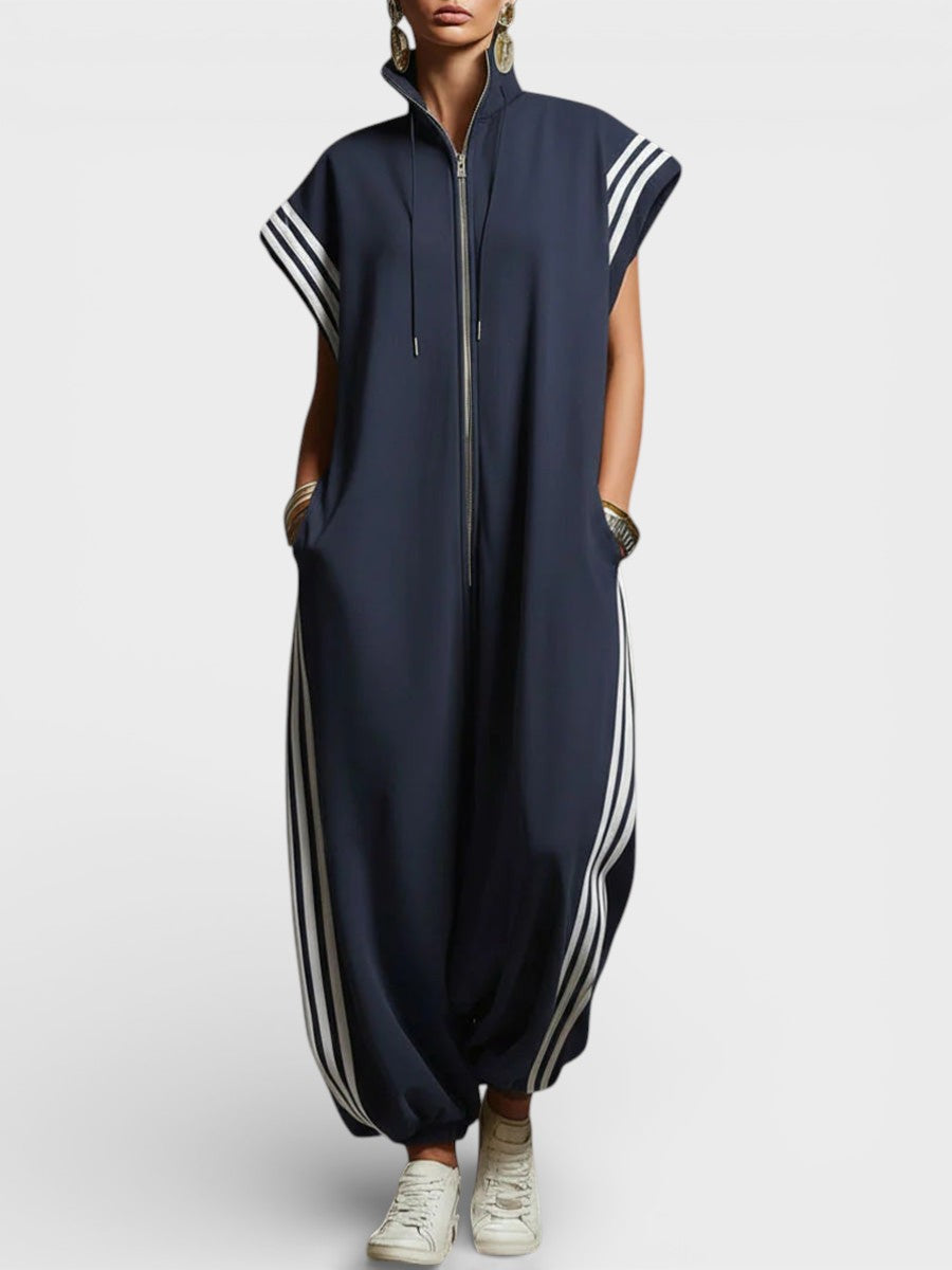 Model in navy blue zip neck jumpsuit with white side stripes and cap sleeves, studio setting.