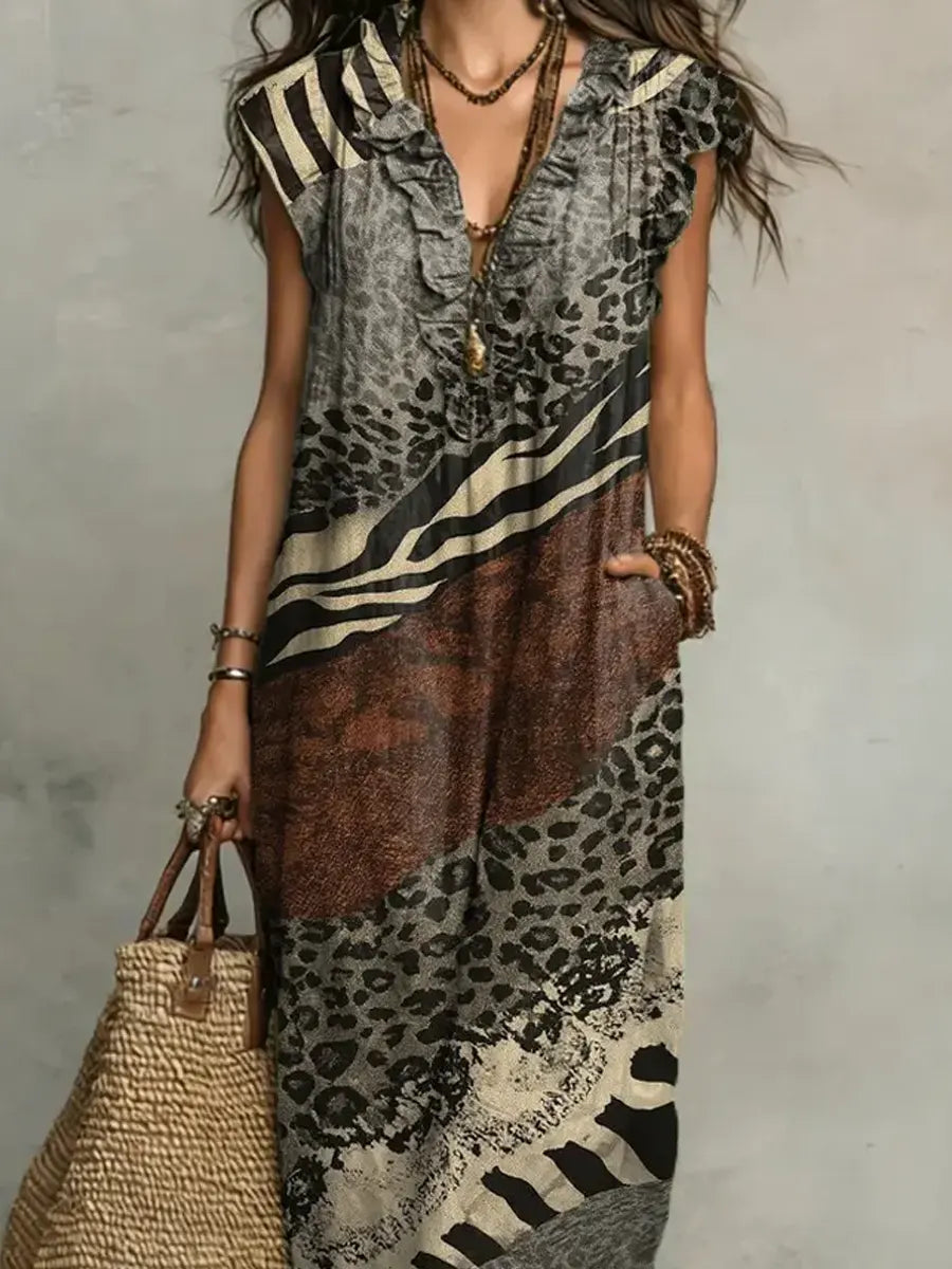 Close-up of mixed print maxi dress with ruffled neckline and layered jewelry in studio setting.
