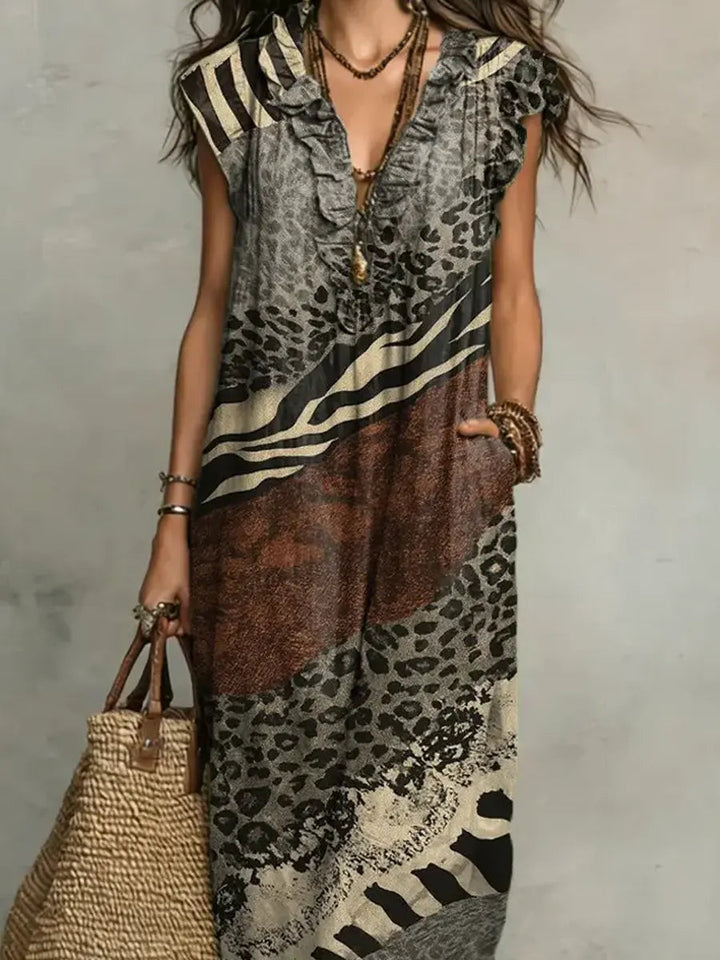Close-up of mixed print maxi dress with ruffled neckline and layered jewelry in studio setting.