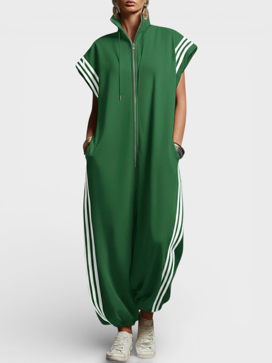 Model wearing green zip neck jumpsuit with white side stripes and cap sleeves, studio background.