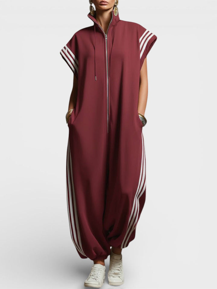 Model showing burgundy zip neck jumpsuit with white side stripes and cap sleeves, studio background.