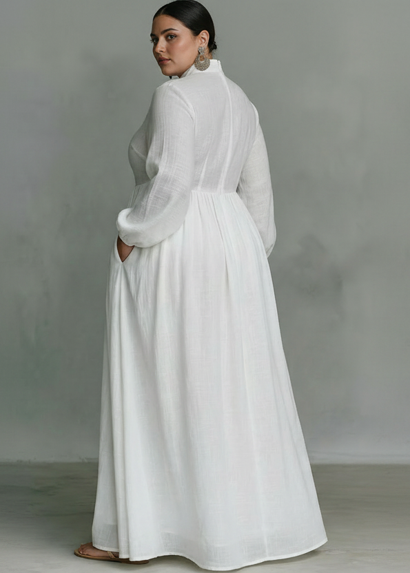Rear view of white flowing button-front maxi dress with long sleeves in a studio setting.