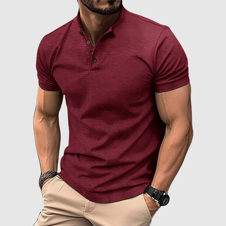 Man wearing a maroon breathable polo shirt with buttoned collar, paired with beige pants, in a studio setting.