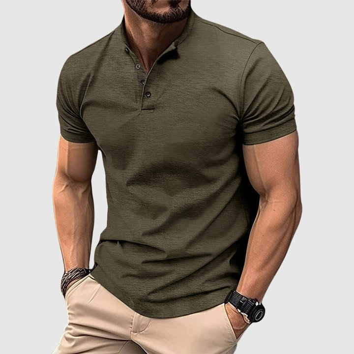 Man wearing a dark green breathable polo shirt with buttoned collar, paired with beige pants, in a studio setting.