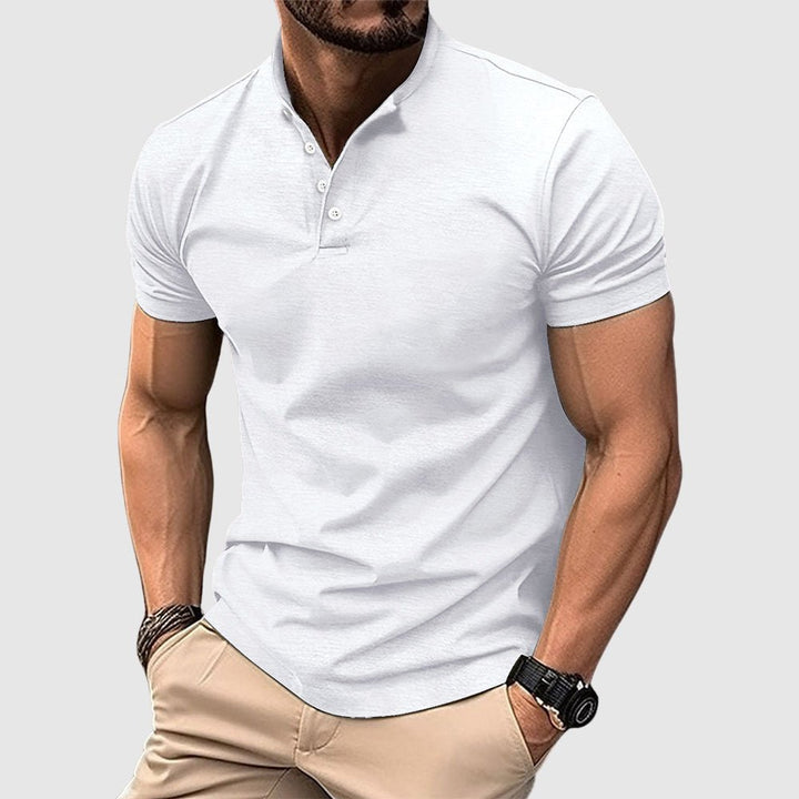 Man wearing a white breathable polo shirt with buttoned collar, paired with beige pants, in a studio setting.