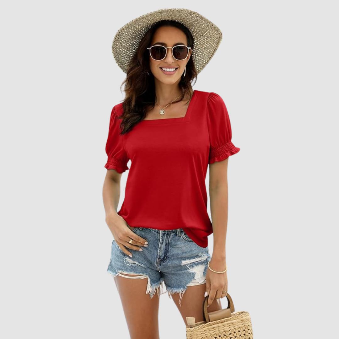 Female model in red square neck top, ripped denim shorts, straw accessories. Neutral backdrop for focus.