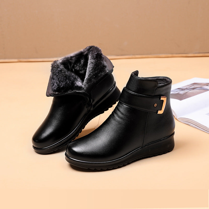 Black ankle boots with soft interior lining, gold buckle detail on side, on a light beige background with an open magazine.