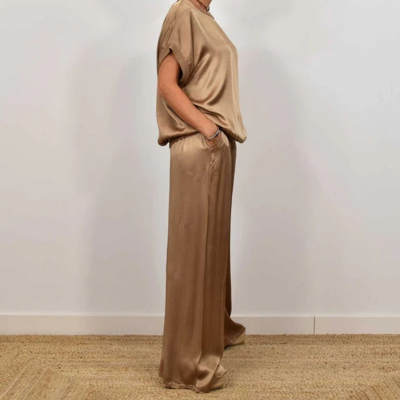 Side view of a chic beige two-piece set with a relaxed top and wide-leg pants, in a white studio setting.