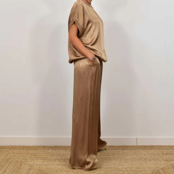 Side view of a chic beige two-piece set with a relaxed top and wide-leg pants, in a white studio setting.