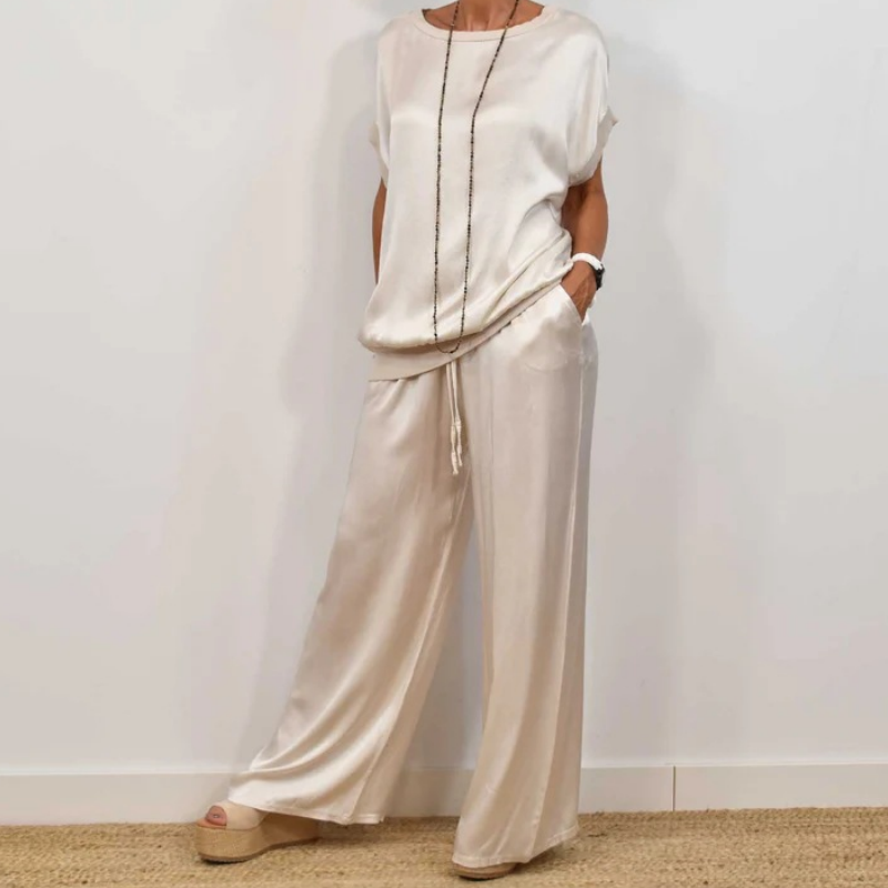 Elegant cream two-piece set with relaxed fit, featuring a flowy top and wide-leg pants, worn with platform sandals in a white studio.