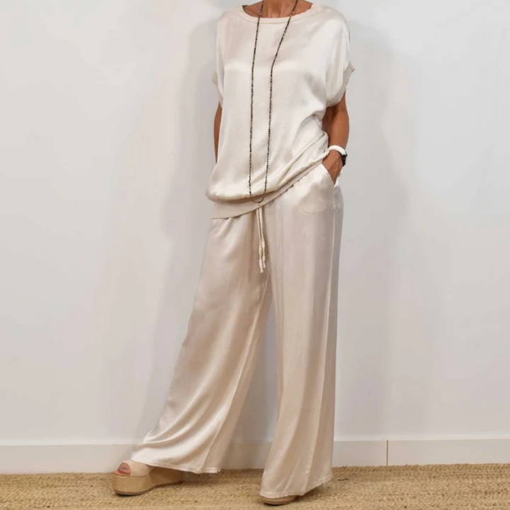 Elegant cream two-piece set with relaxed fit, featuring a flowy top and wide-leg pants, worn with platform sandals in a white studio.