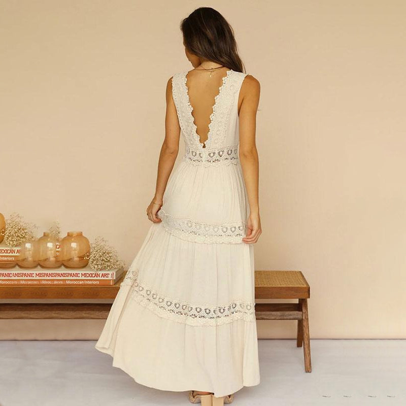 Back view of woman in cream maxi dress with lace design, in a cozy room setting.