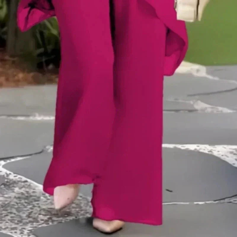 Bottom view of magenta pants; worn outdoors with foliage background.