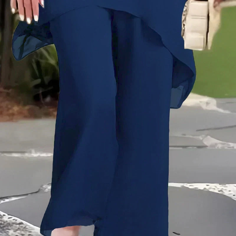 Bottom view of navy blue pants; worn outdoors with foliage background.
