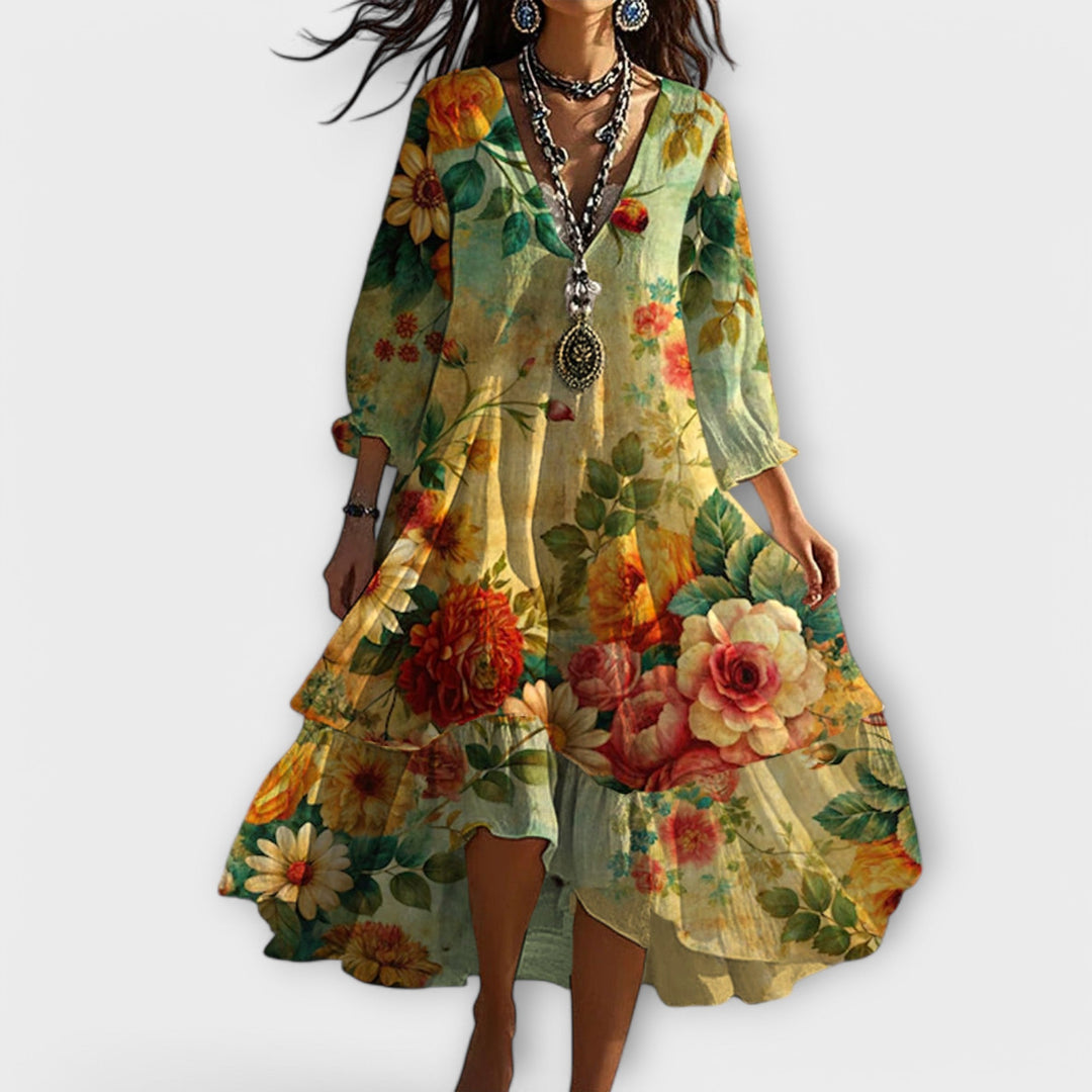 Model wearing a vintage floral dress with vibrant flowers on a gradient, flowing fabric, set against a plain white background.