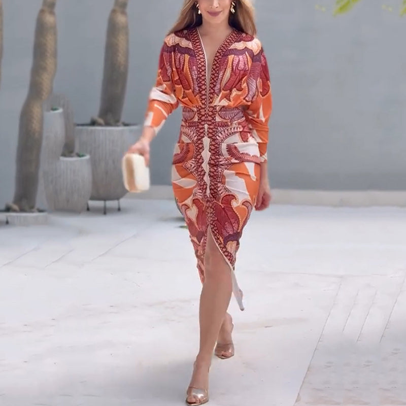 Chic V-neck dress with bold red and orange patterns, elegantly worn by a model in a sleek outdoor setting.
