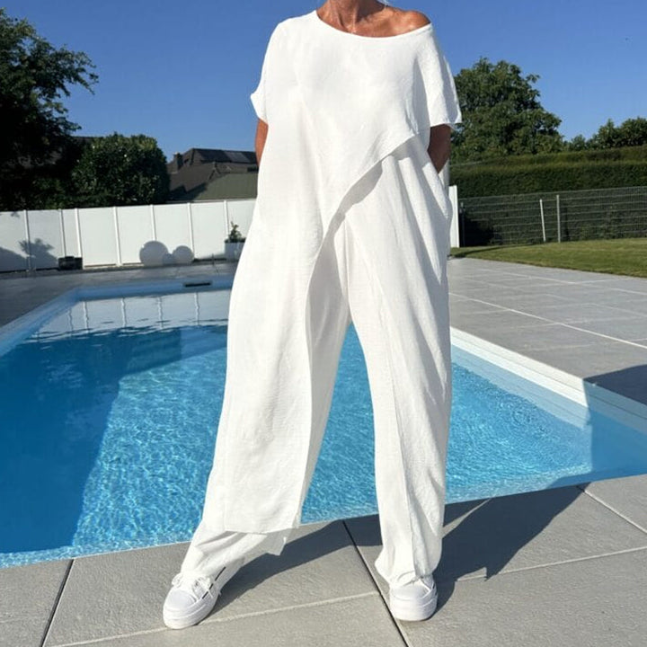 White off-shoulder two-piece outfit, featuring wide-leg pants and a relaxed fit, showcased by a pool under a clear blue sky.