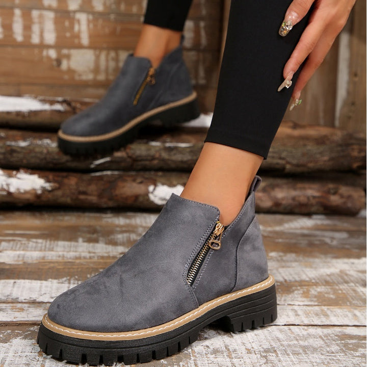 Gray ankle boots with zipper detail, shown on wooden floor with leggings.