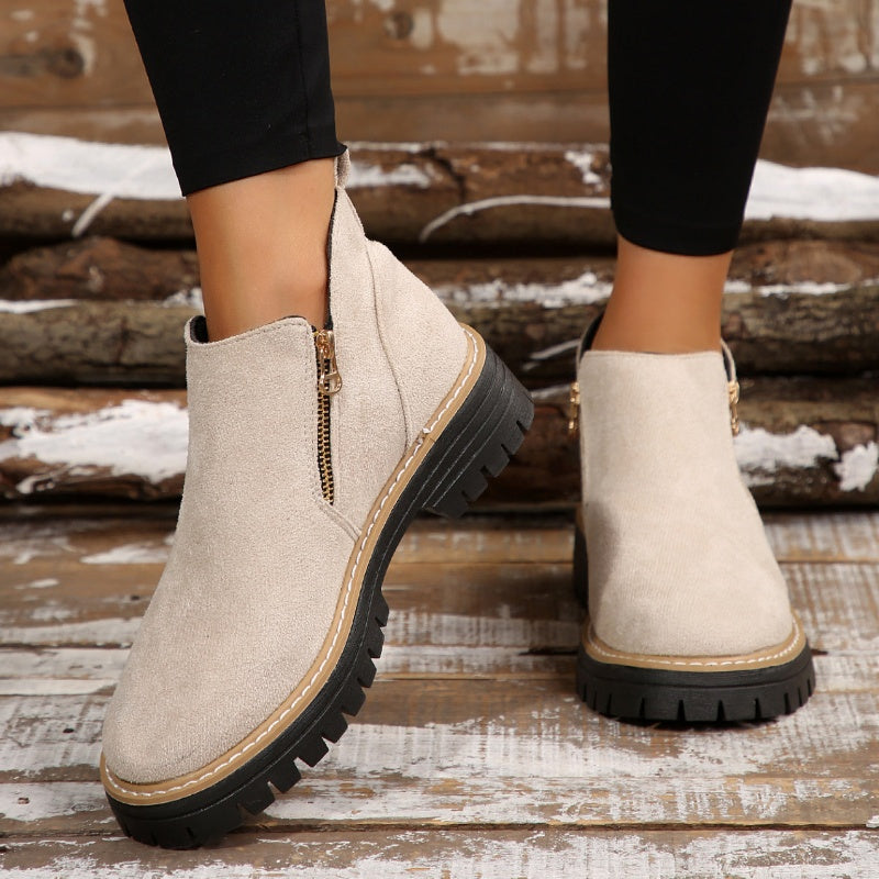 Cream ankle boots with zipper, worn with leggings on rustic wooden floor.