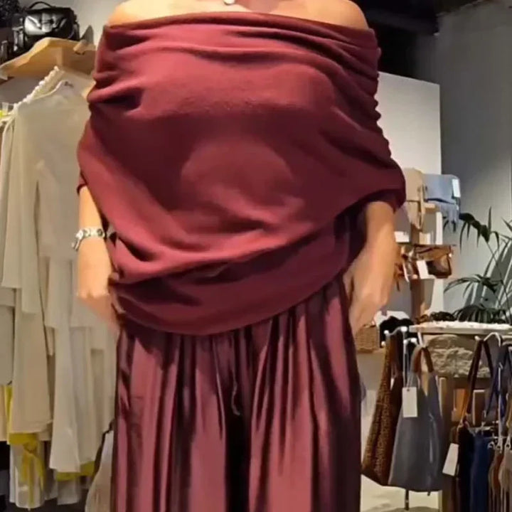 Close-up of a burgundy off-shoulder top and wide pants in a modern retail store.