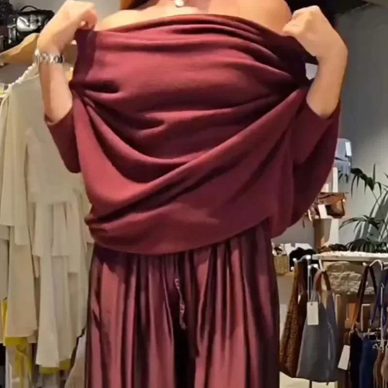 Model adjusting a burgundy off-shoulder top, showcasing a flowy design in a stylish shop setting.