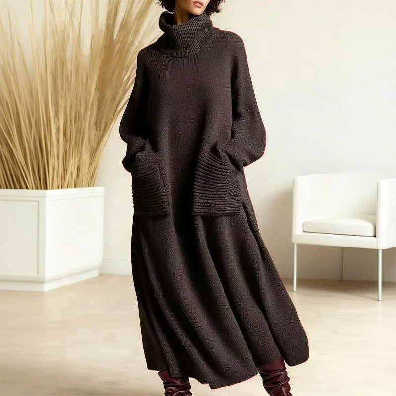 Sophisticated dark brown sweater dress showing a high neck and roomy pockets, showcased in a plain indoor space with beige tones and a white chair.