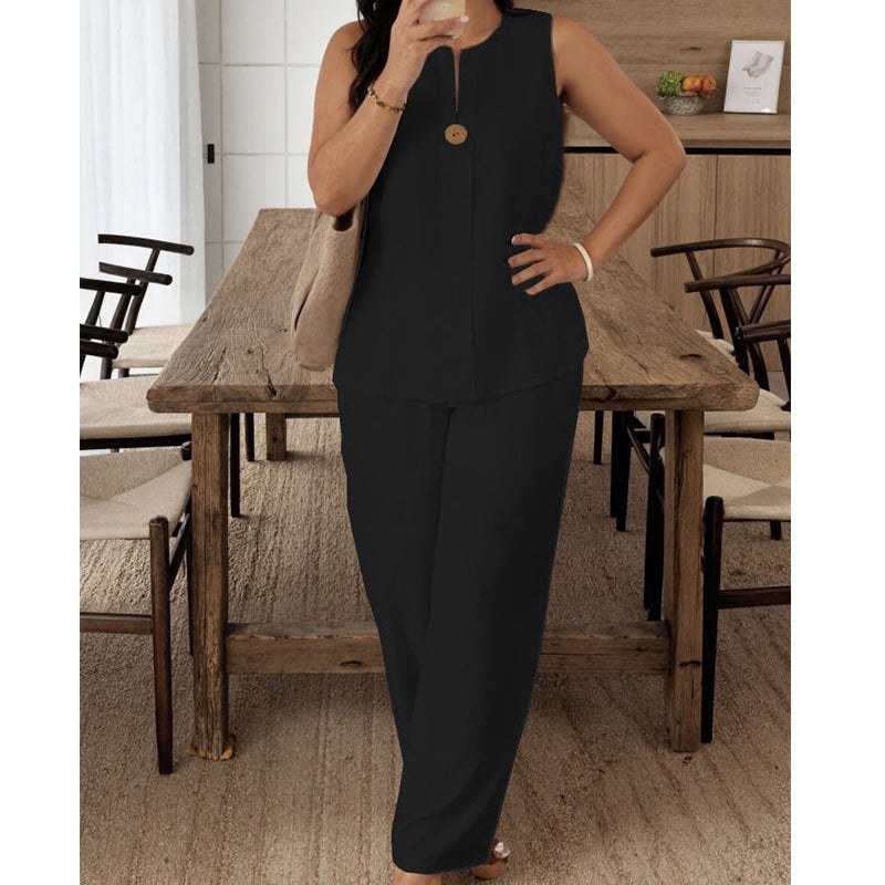 Elegant black sleeveless top and pants set modeled in a cozy dining room with rustic wooden chairs and a beige textured rug.