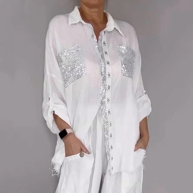 White elegant set with sequin pockets and button detailing, worn by model in gray studio.