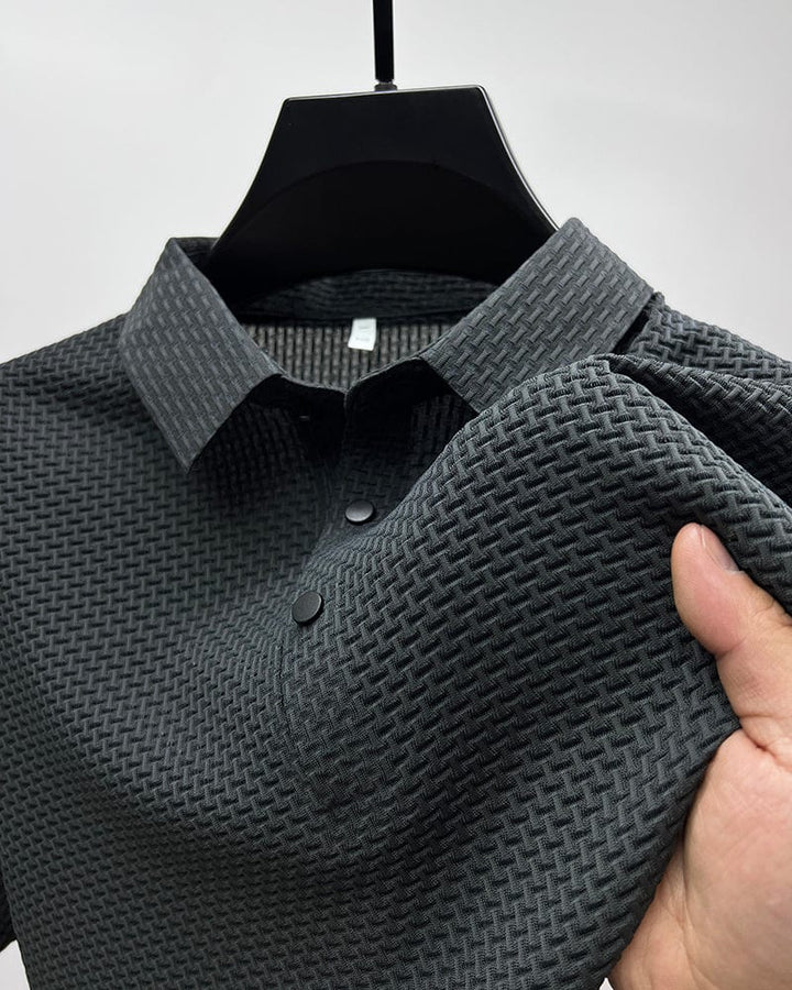 Dark gray textured polo shirt on hanger, close-up of collar and buttons, hand touching fabric in studio.
