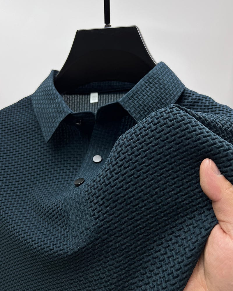 Navy blue textured polo shirt on hanger, close-up of collar and buttons, hand touching fabric in studio.