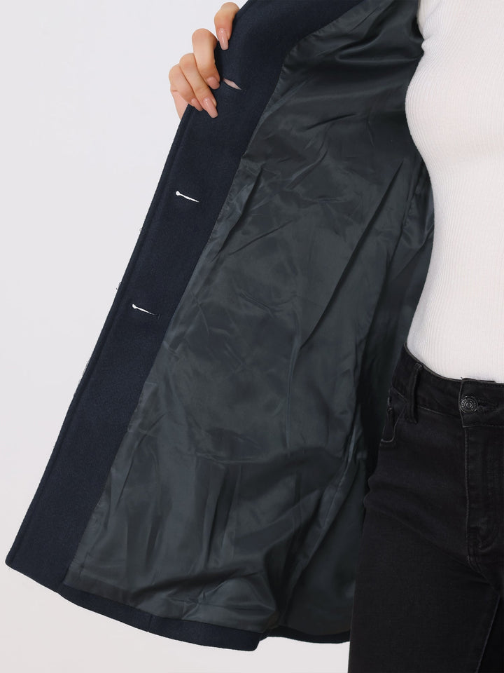 Inside view of a navy blue coat lining, held open by a person wearing jeans.