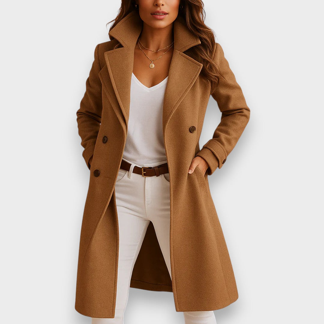 Model featuring a brown classic coat with a white top and beige pants, studio background.