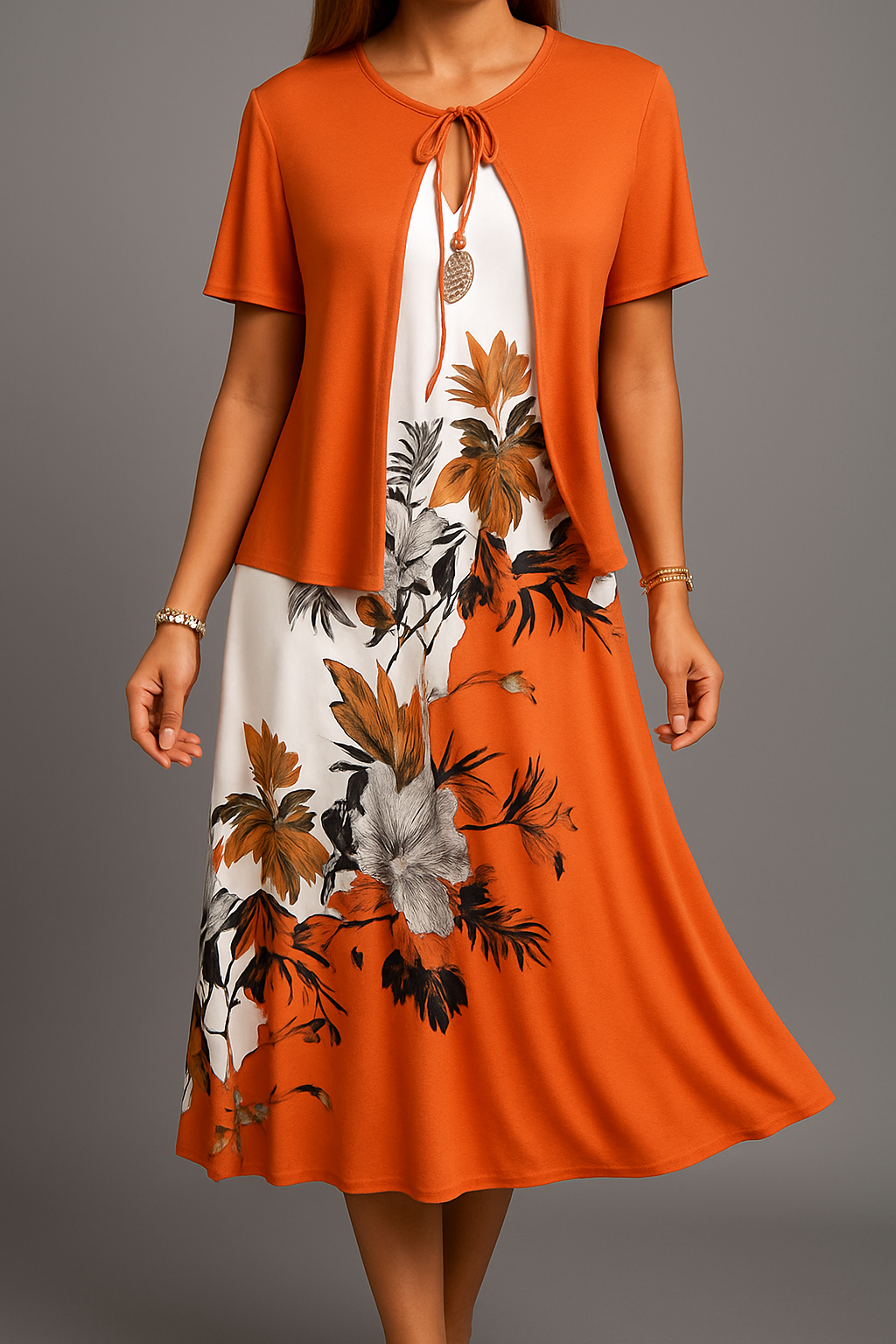 Orange short-sleeve midi dress with floral print, featuring a tied neckline, modeled in a studio setting.
