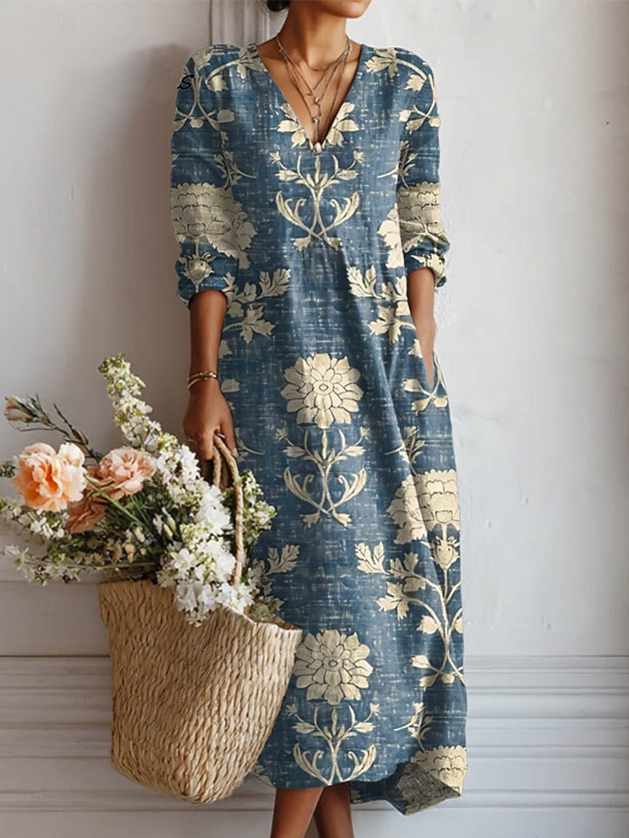 Woman wearing blue dress with floral print, carrying a woven basket of flowers, white indoor background.