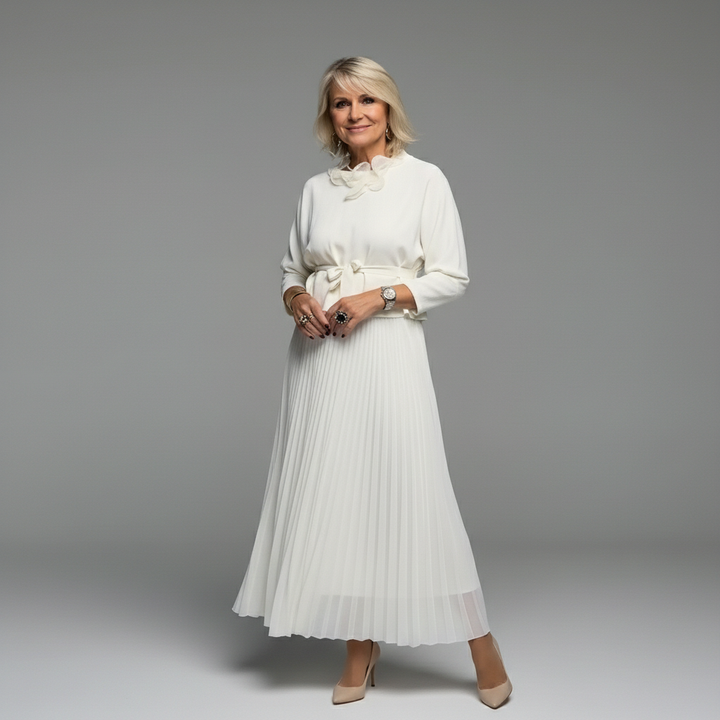 Stylish woman wearing a white pleated dress with decorative neckline, outdoor urban setting.