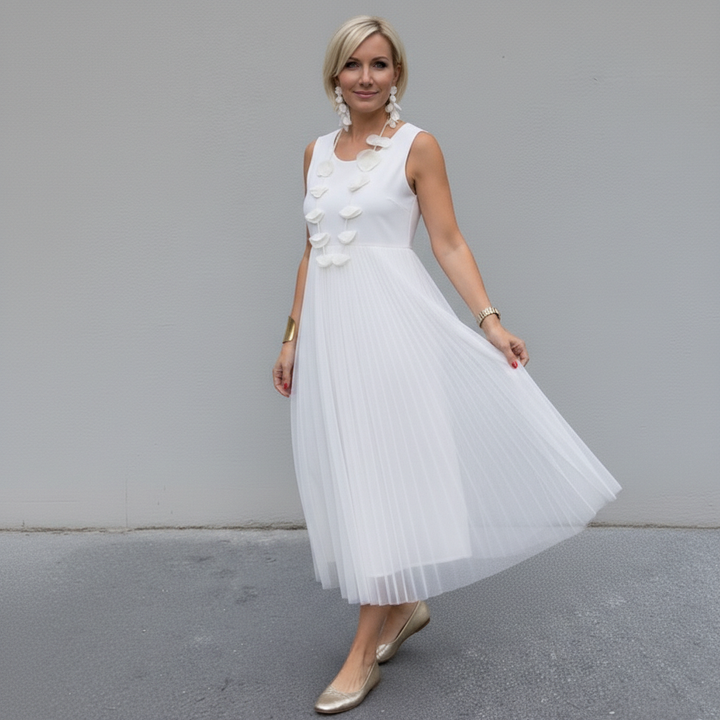 Elegant woman wearing a white dress with pleated skirt, outdoor urban setting.