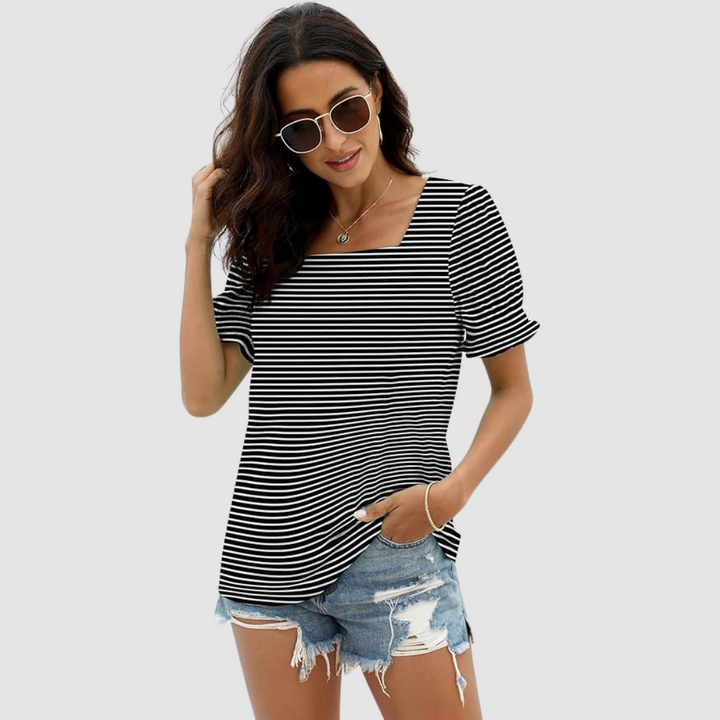 Model wearing black and white striped top, denim shorts, sunglasses. Simple studio background accentuates style.