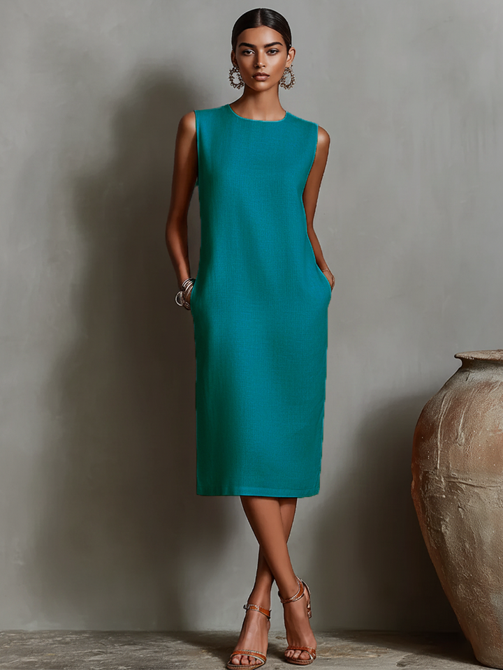 Teal midi dress with pockets, sleeveless, featured on model in sophisticated studio backdrop.
